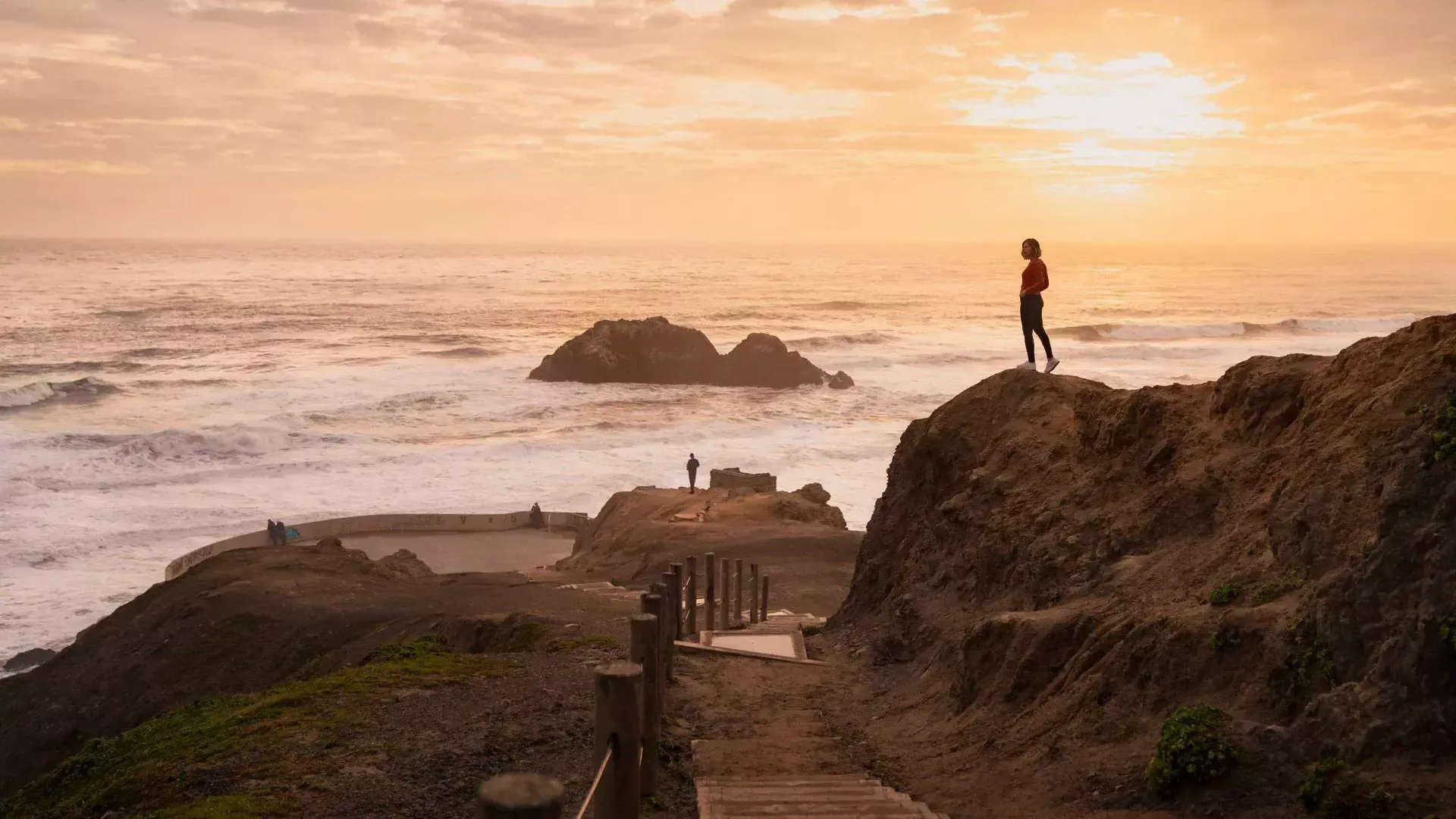 Duas pessoas estão em cima de pedras com vista para o oceano em Sutro Baths, em São Francisco.